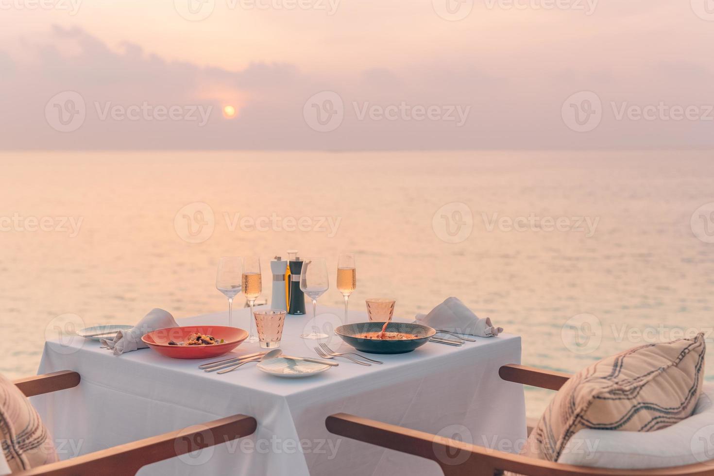 vista del paisaje marino bajo la luz del atardecer con mesa de comedor con piscina infinita alrededor. escapada tropical romántica para dos, concepto de pareja. sillas, comida y romance. comedor de destino de lujo, plantilla de luna de miel foto