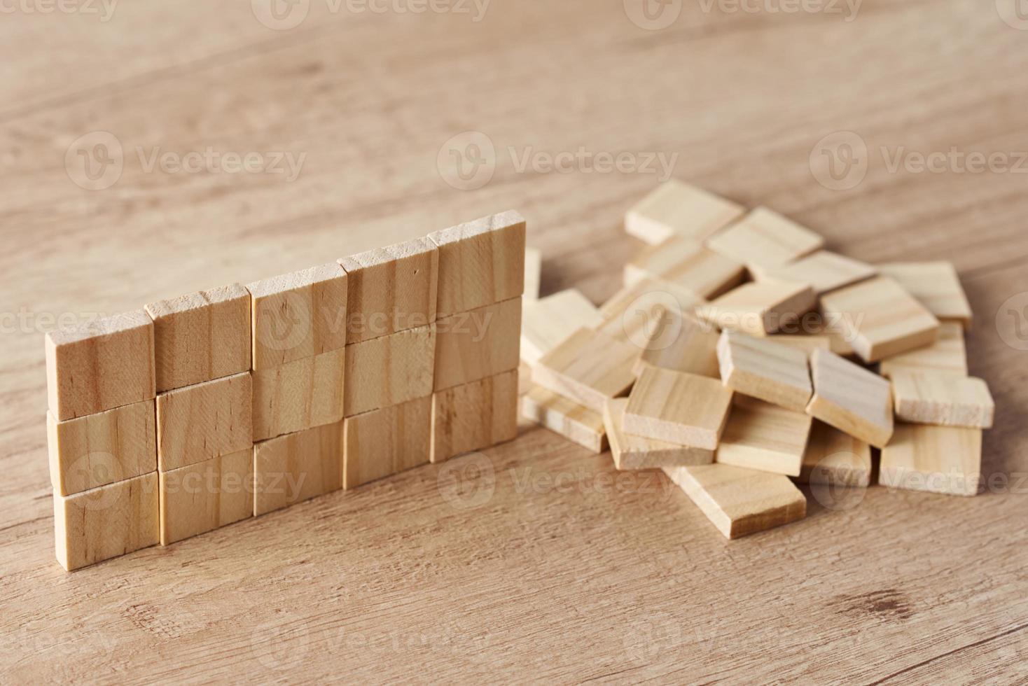Wall made of wooden blocks on the wood table. Finishing task concept photo