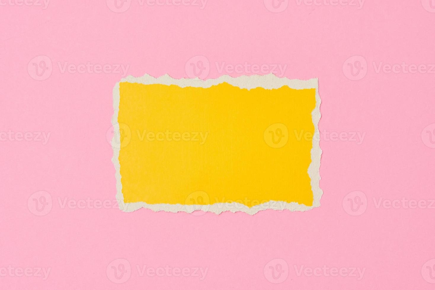 Ripped yellow paper torn edge sheet on a pink background. photo