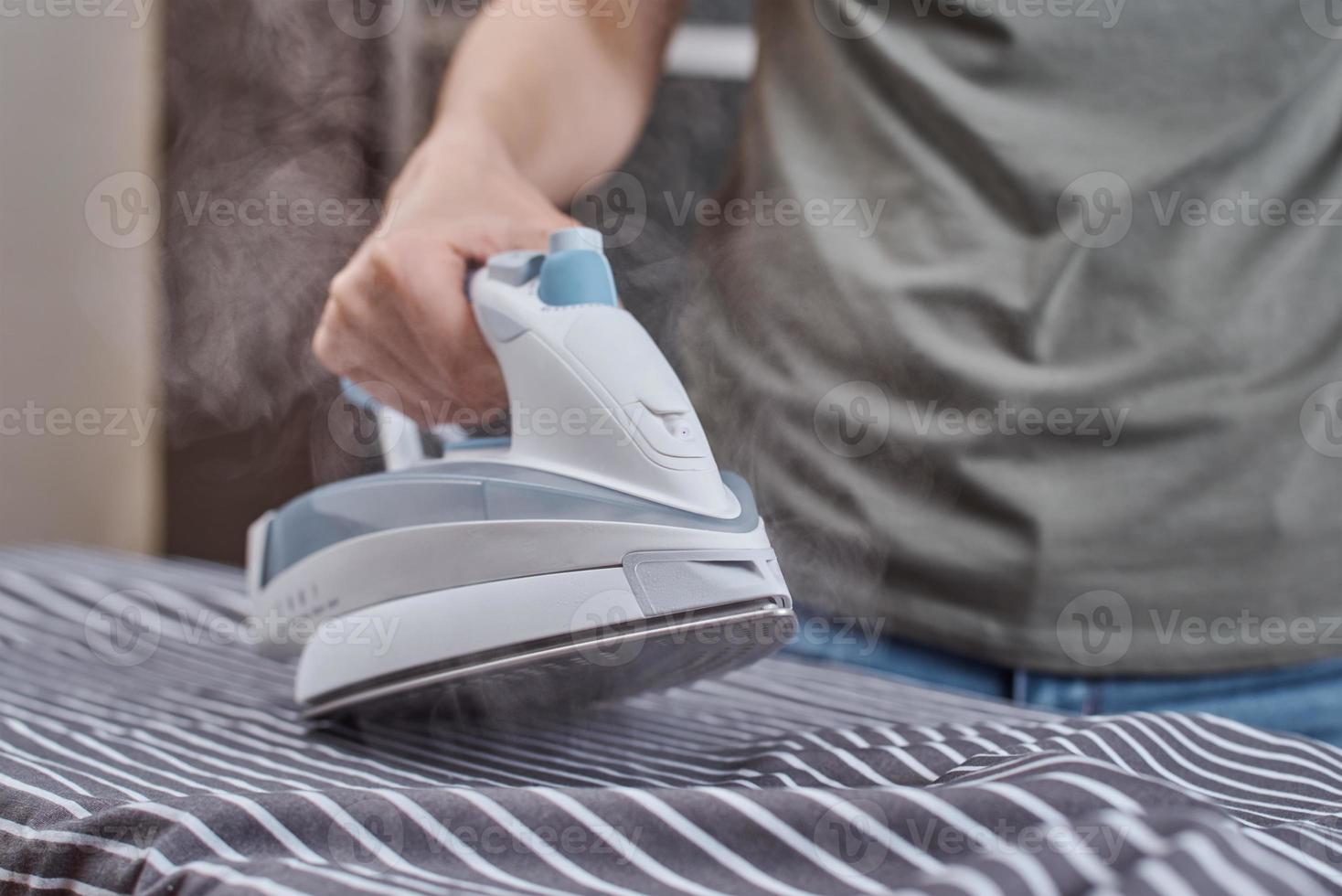 Steam boost on the modern iron. Woman ironing clothes with modern iron photo