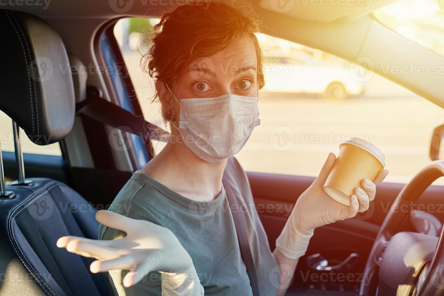 Woman in mask drink coffee in the car photo