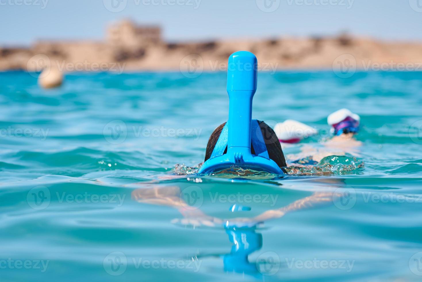 mujer con una máscara facial completa de snorkel buceando en el mar azul. vacaciones de verano foto