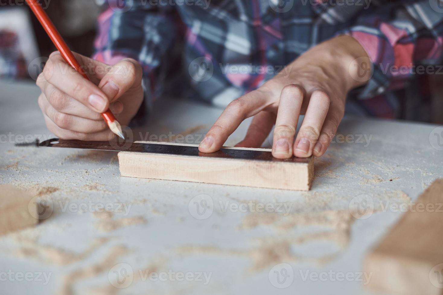 Carpenter hands taking measurement with a pencil of wooden plank. photo