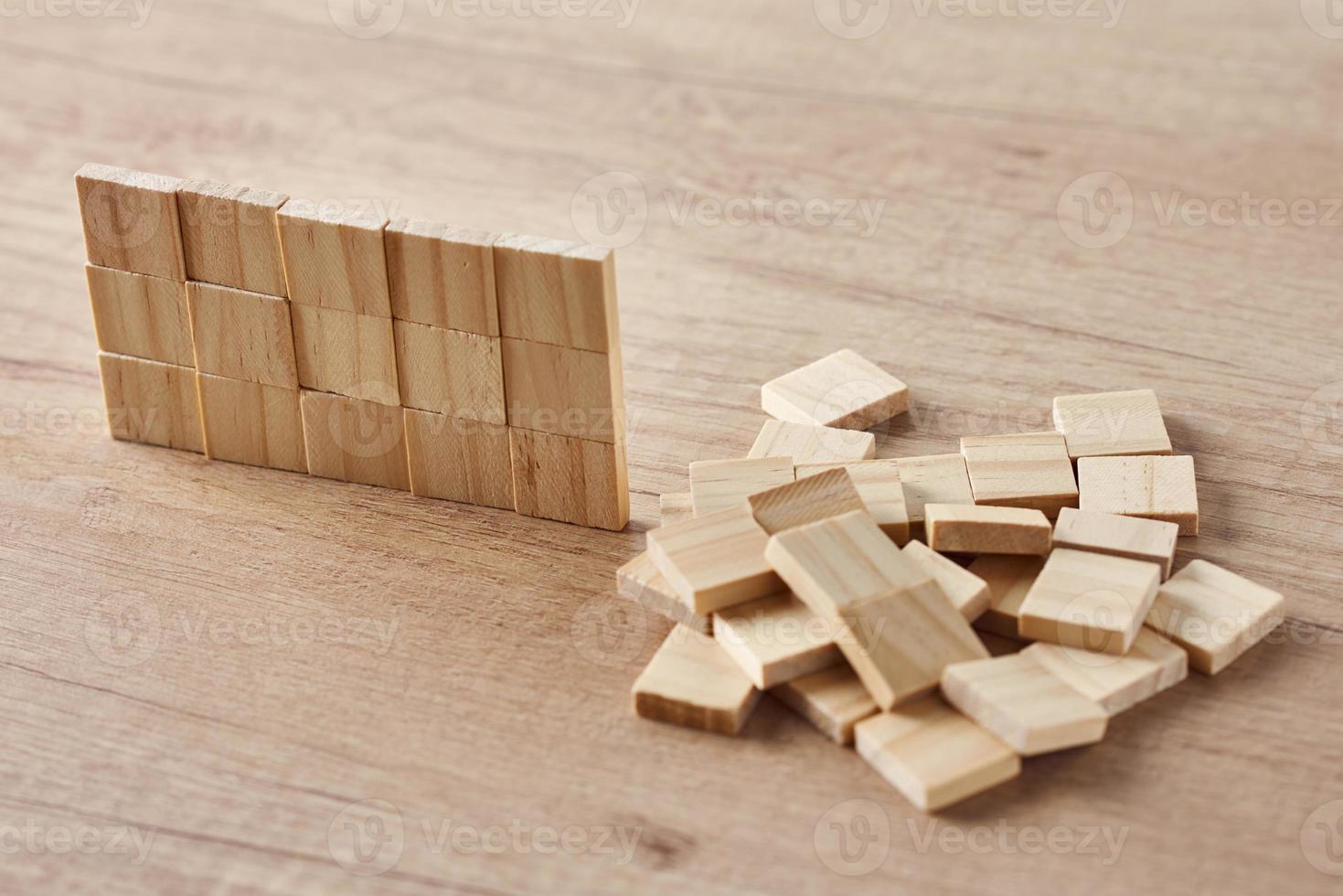 Wall made of wooden blocks on the wood table. Finishing task concept photo