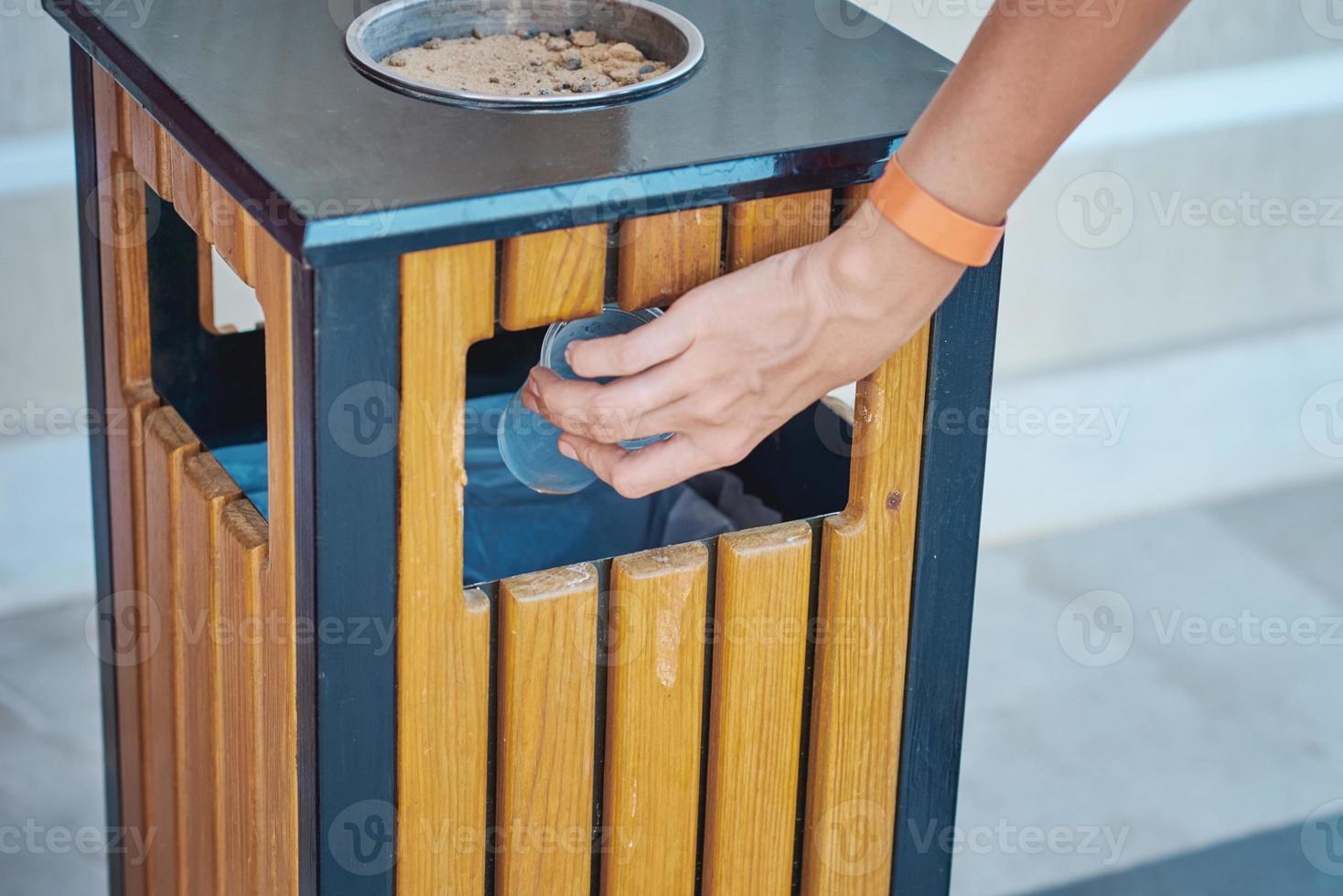 Woman hand throwing plactic cup for water in a trash bin photo
