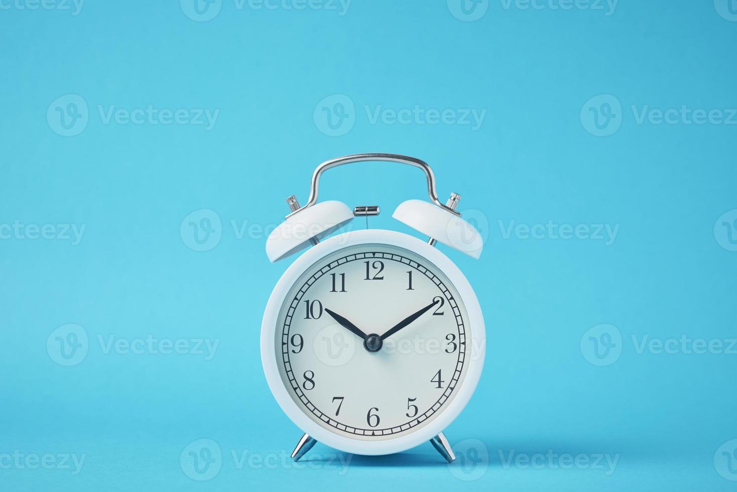 Vintage white alarm clock on the blue backround with copy space. Time concept photo