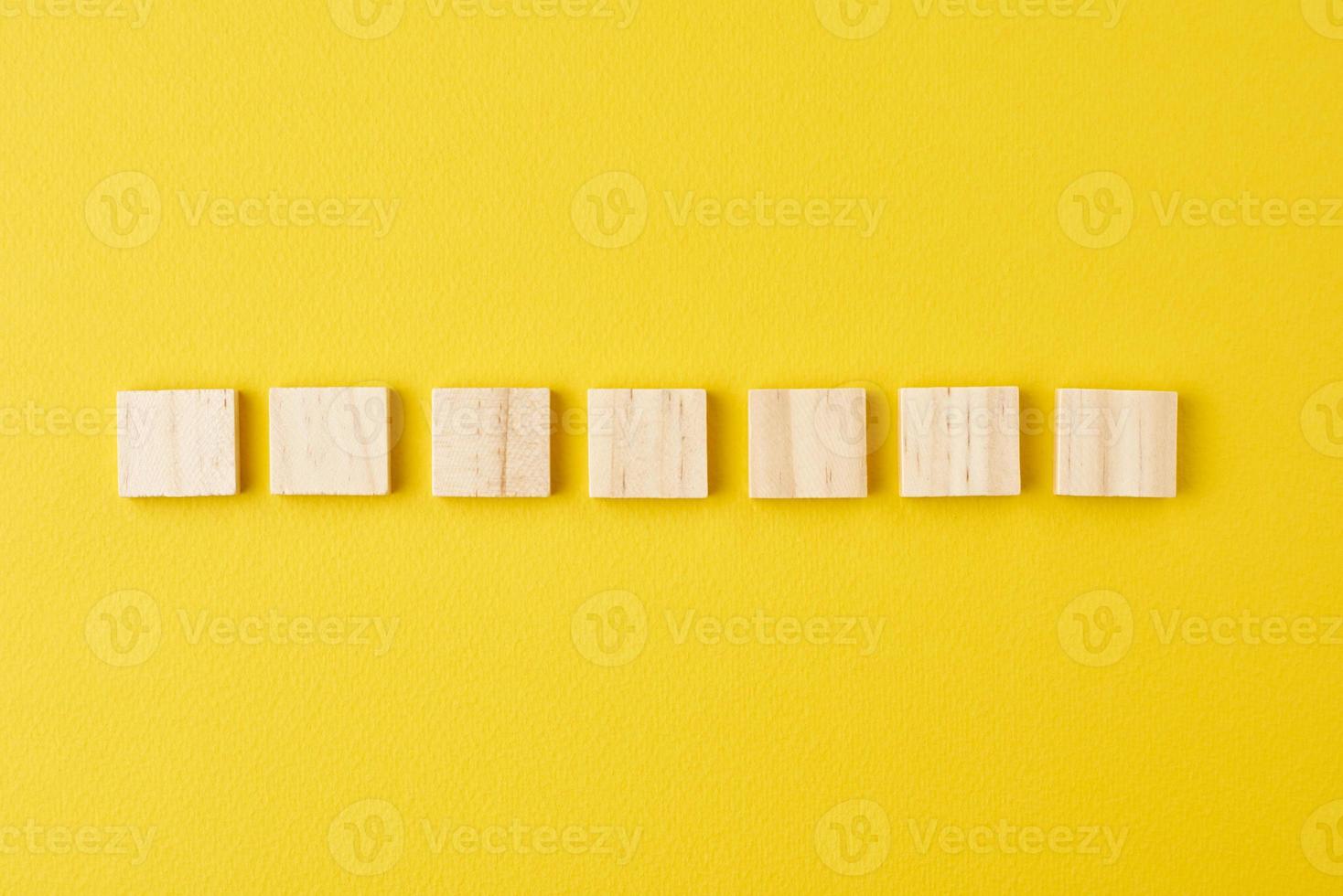Wooden blocks in row on the yellow background, top view photo