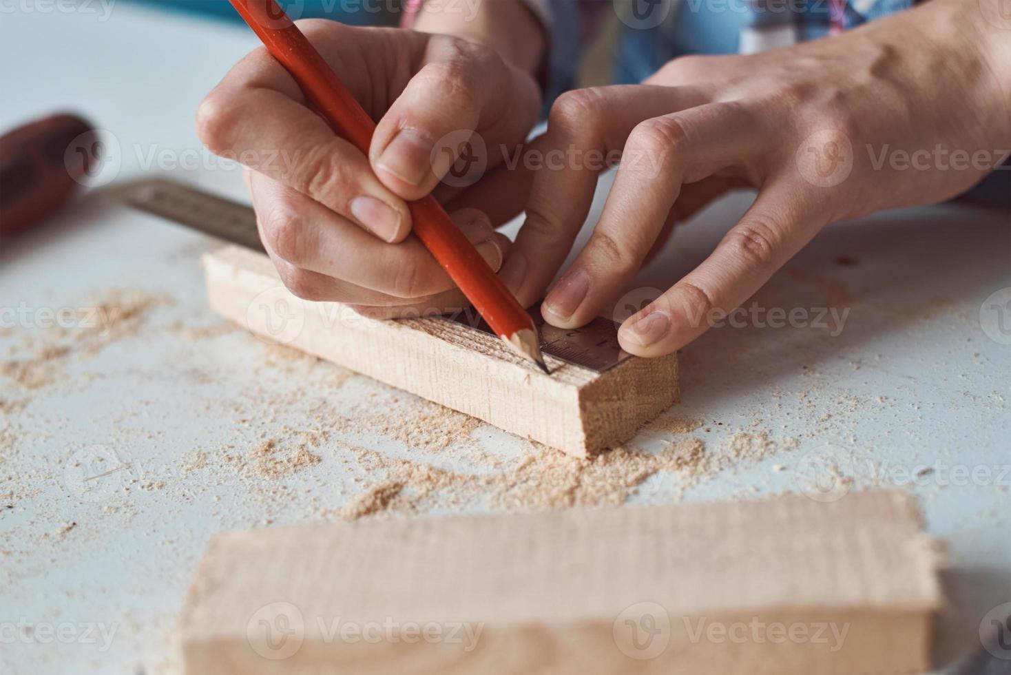 Carpenter hands taking measurement with a pencil of wooden plank. photo