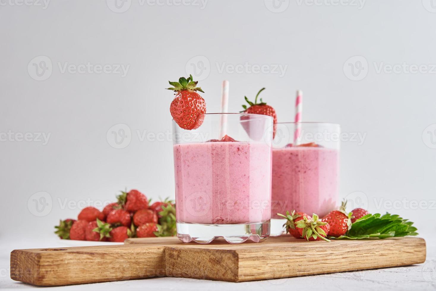 batido de fresa en vaso con paja y bayas frescas foto