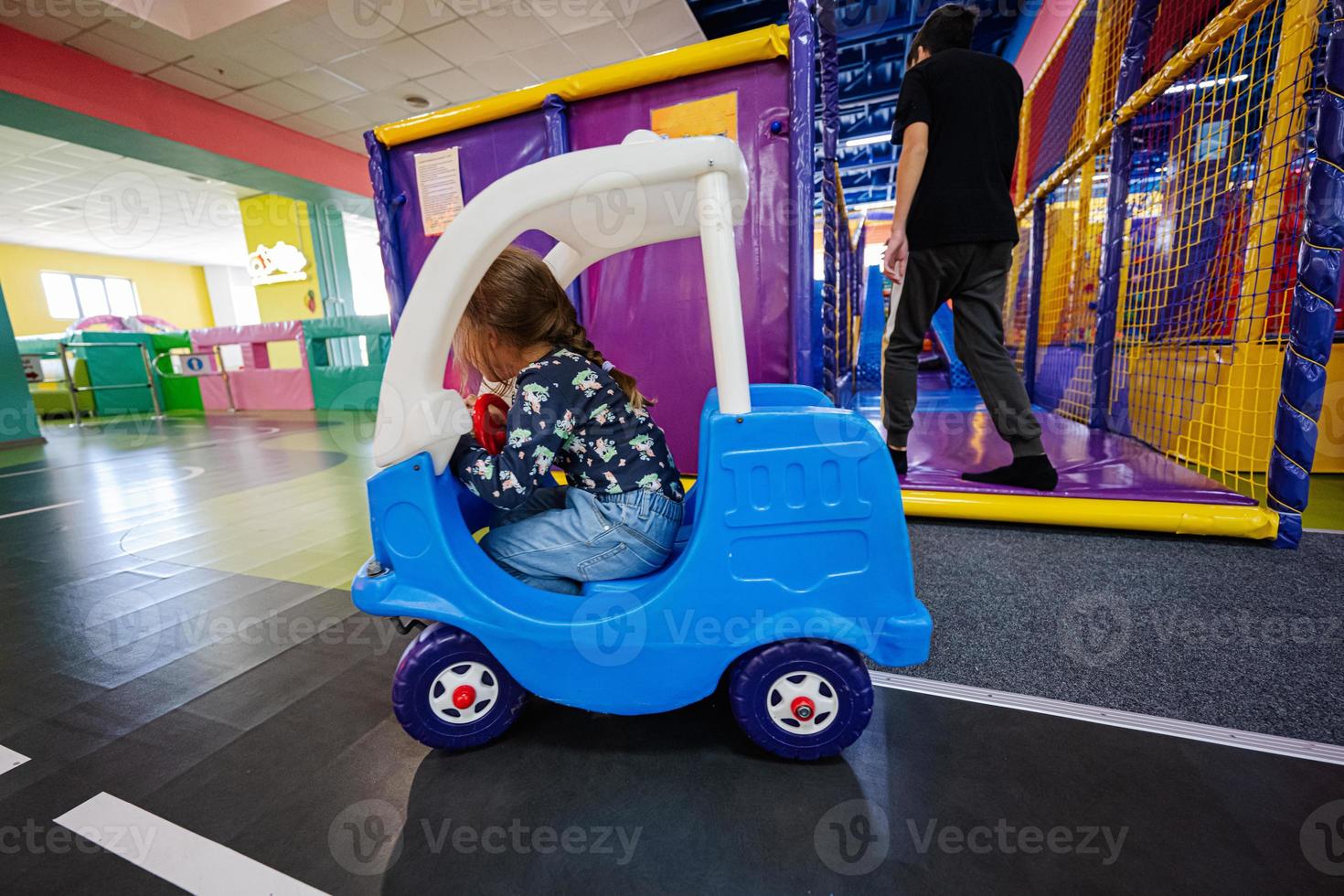 niños jugando en el patio interior del centro de juegos, niña en coche de juguete. foto