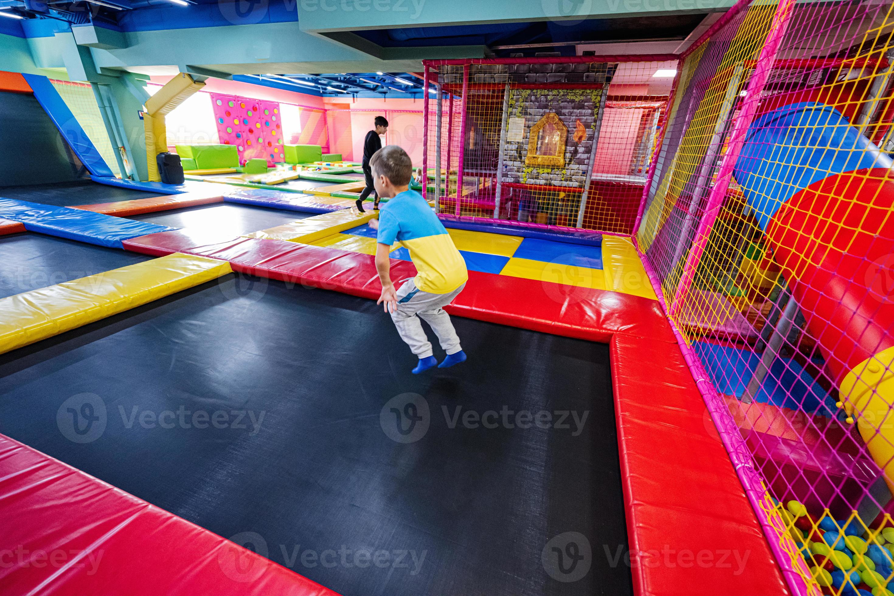 Happy kids playing at indoor play center playground. Boy jumping on