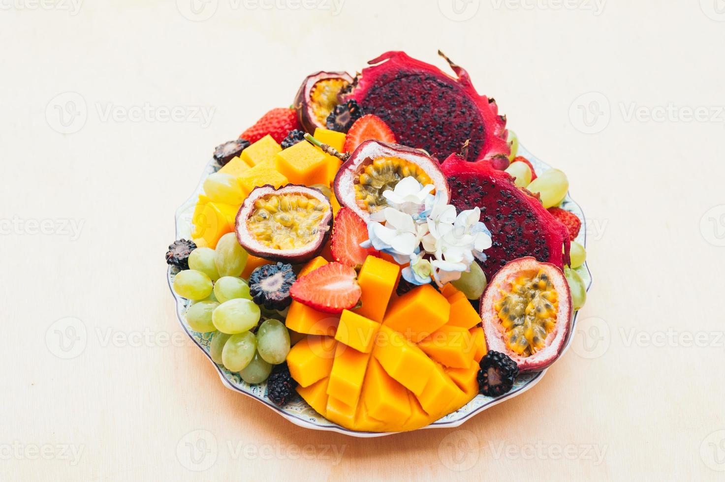 pitaya roja, pitahaya, uvas, mango y fresa en un plato con fondo blanco. buena nutrición, fruta rica en vitaminas. ensalada fresca. frutas tropicales foto