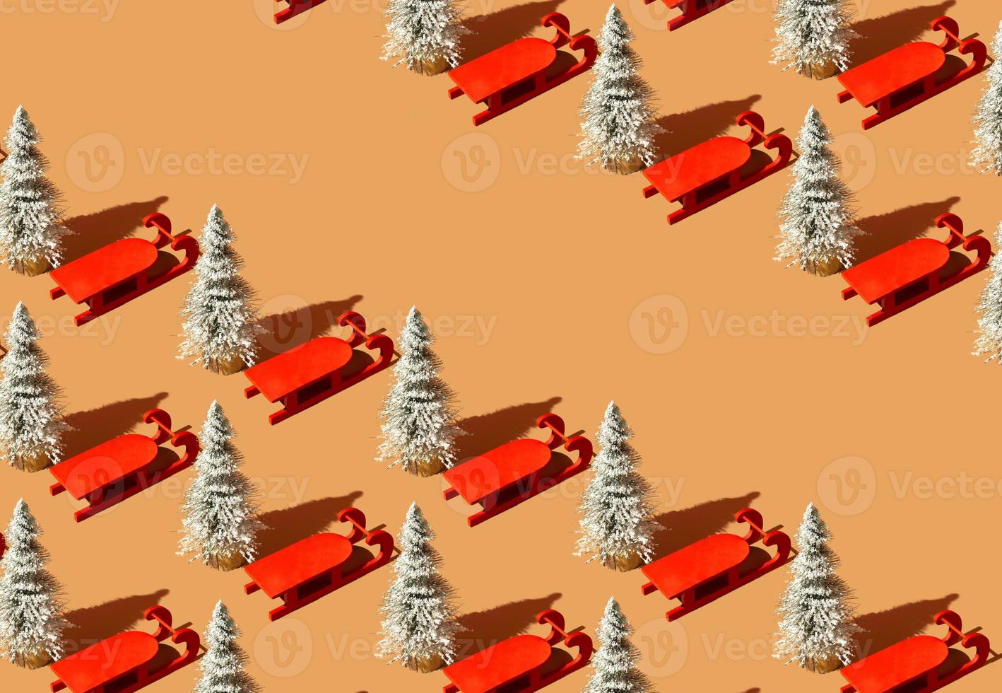 Pattern made with Christmas tree and red sleigh against pastel orange background. Christmas holiday idea. Minimal winter retro concept with copy space. photo