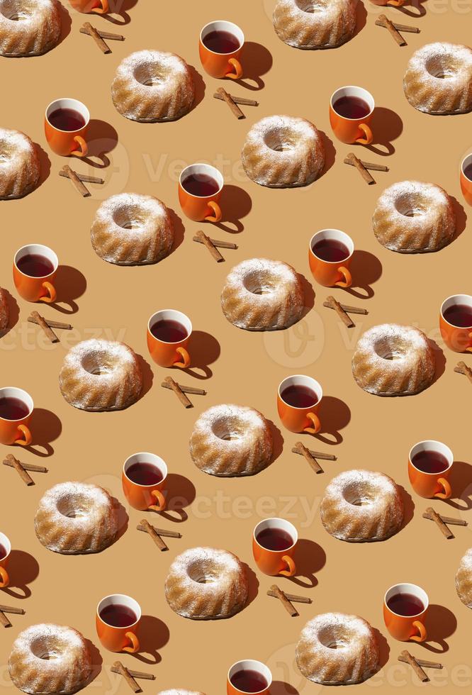 Creative retro pattern made of a tea or coffee cup, bundt cake and cinnamon stick. Winnter mood idea. Cosy Christmas breakfast theme. photo