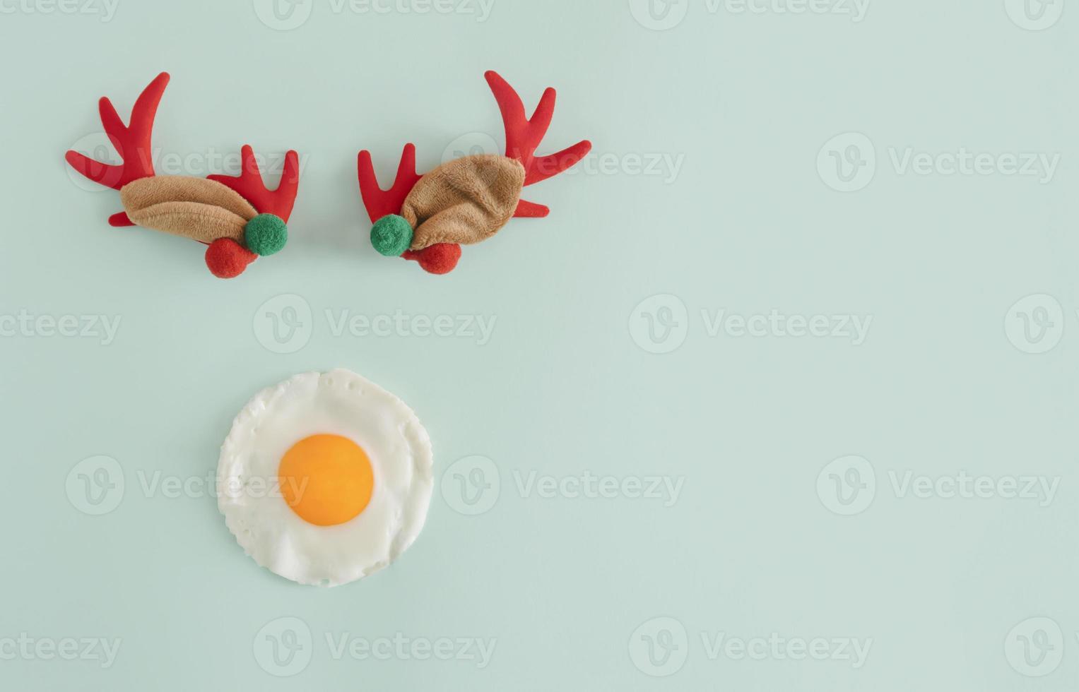 Creative flat lay concept of a reindeer with a poached egg instead of a nose against light pastel mint green color. Christmas and food theme idea with copy space. photo