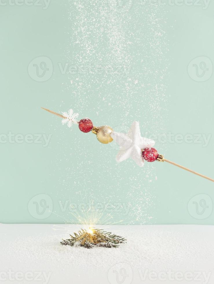 Skewer made of a Christmas decoration and baked on an smal fir twigs while snow falling around.  Christmas theme color vibes. Winter concept. photo