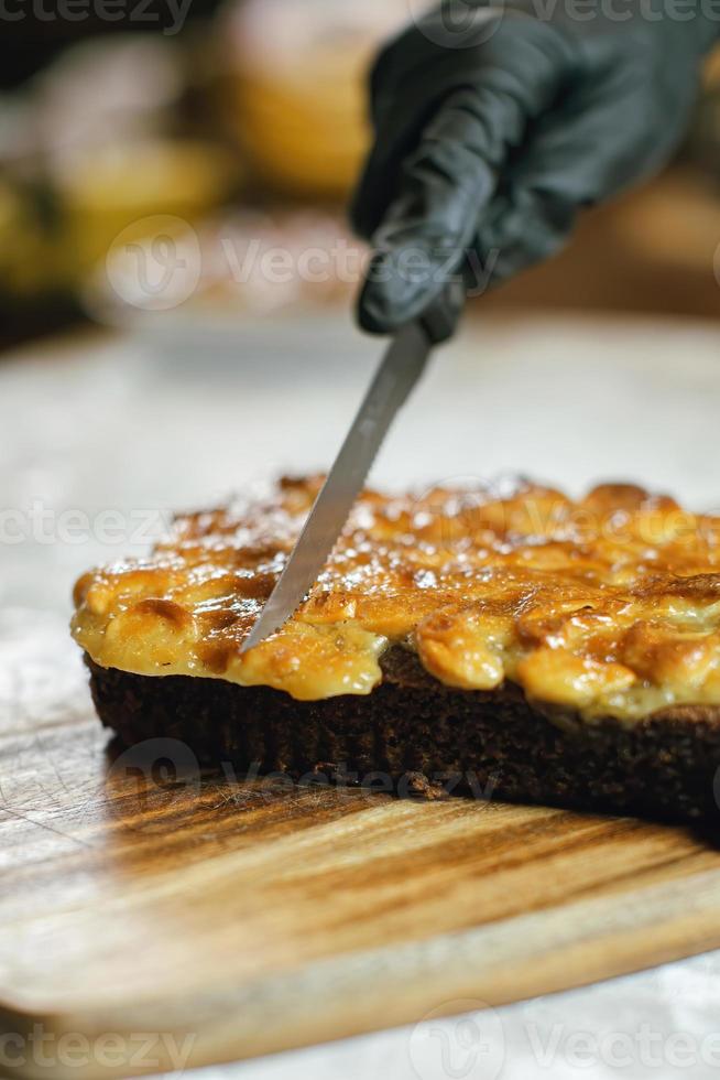 pastel de toffee cortado por el chef en tabla de cortar de madera, postre delicioso, postre para una taza de café, panadería casera foto