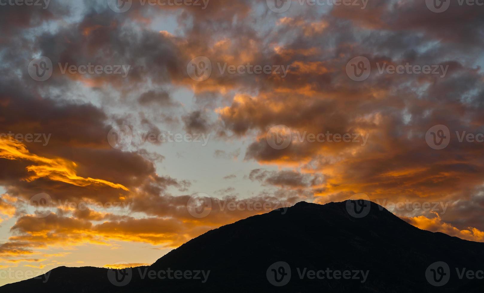 Dawn in the mountains, the first rays of the sun on the red clouds over the mountain. The mountains are in deep shadow, an idea for a background. Mediterranean coast. photo