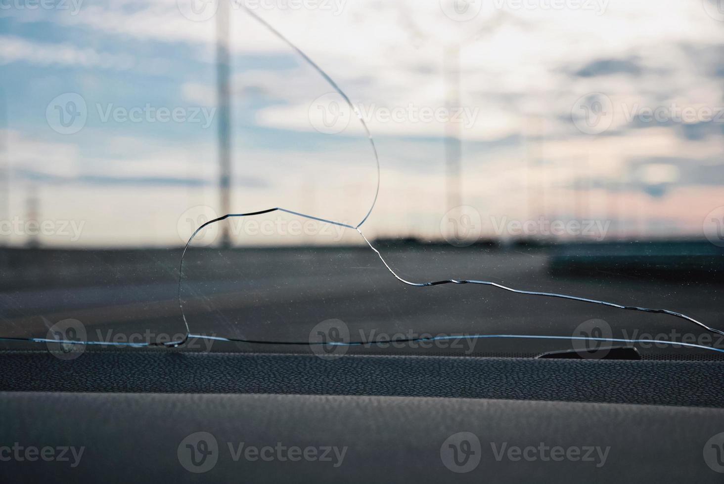 grietas en el cristal del parabrisas del coche golpeadas por piedras expulsadas por debajo de las ruedas de otro coche foto