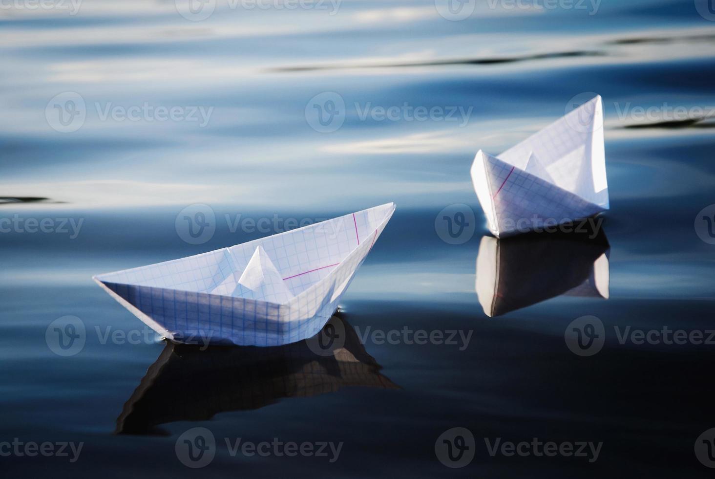 Paper boats floating in blue water photo