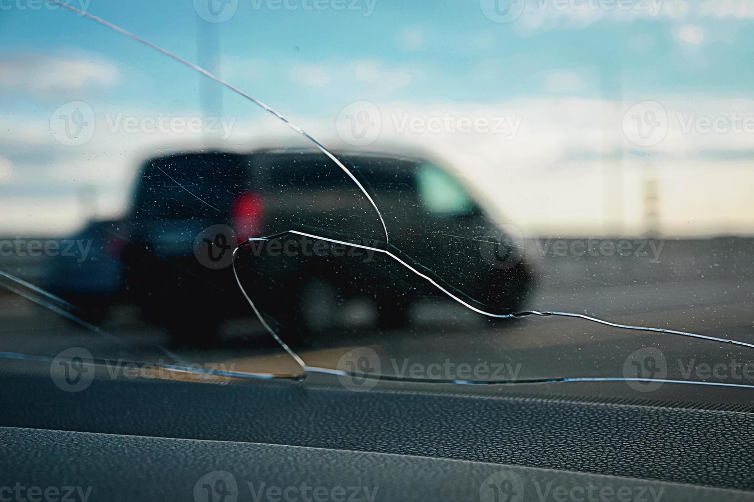 vista a través de cristales rotos en la carretera, parabrisas de coche destrozado por piedra foto