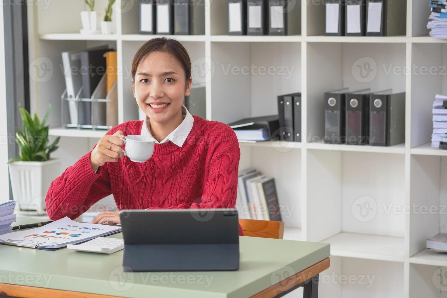 Marketing, Finance, Accounting, Planning, A female accountant holds a coffee cup and uses a laptop computer and documents, charts, graphs in company analysis is profit. photo