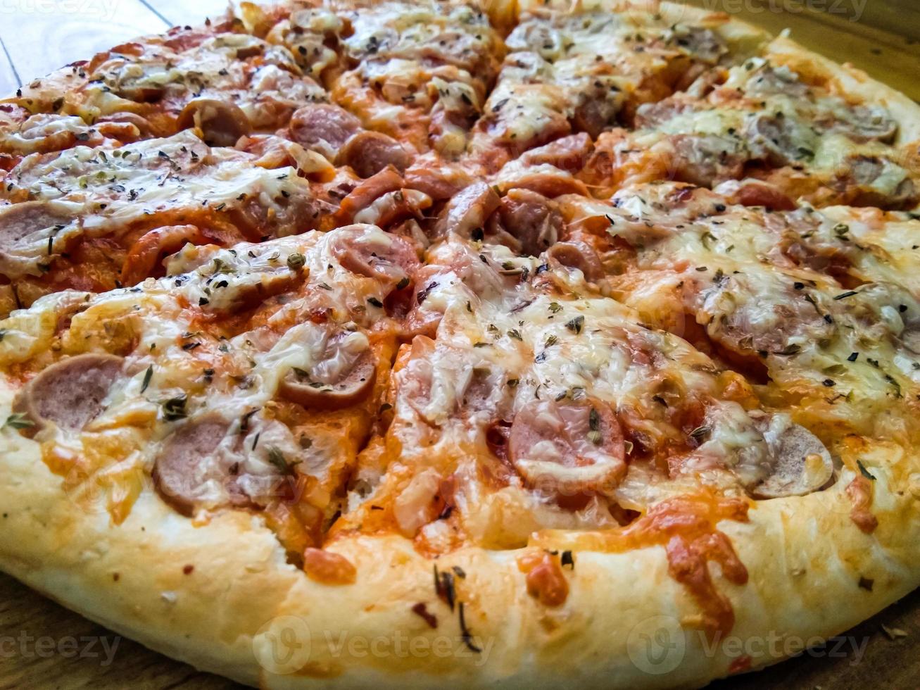 pizza casera con coberturas simples, mozzarella y salchichas en una bandeja de madera foto