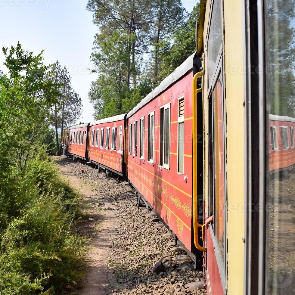 Toy Train moving on mountain slopes, beautiful view, one side mountain, one side valley moving on railway to the hill, among green natural forest. Toy train from Kalka to Shimla in India, Indian Train photo