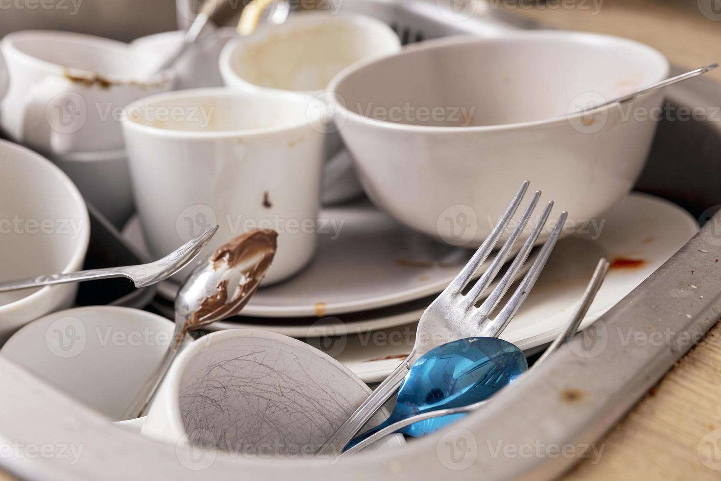 Pile of unwashed, dirty dishes in the sink. Mess in the kitchen. Dirty kitchenware, plates and mugs. Chaos at home. Laziness. Cluttered apartment. Messy cutlery and dishware. photo