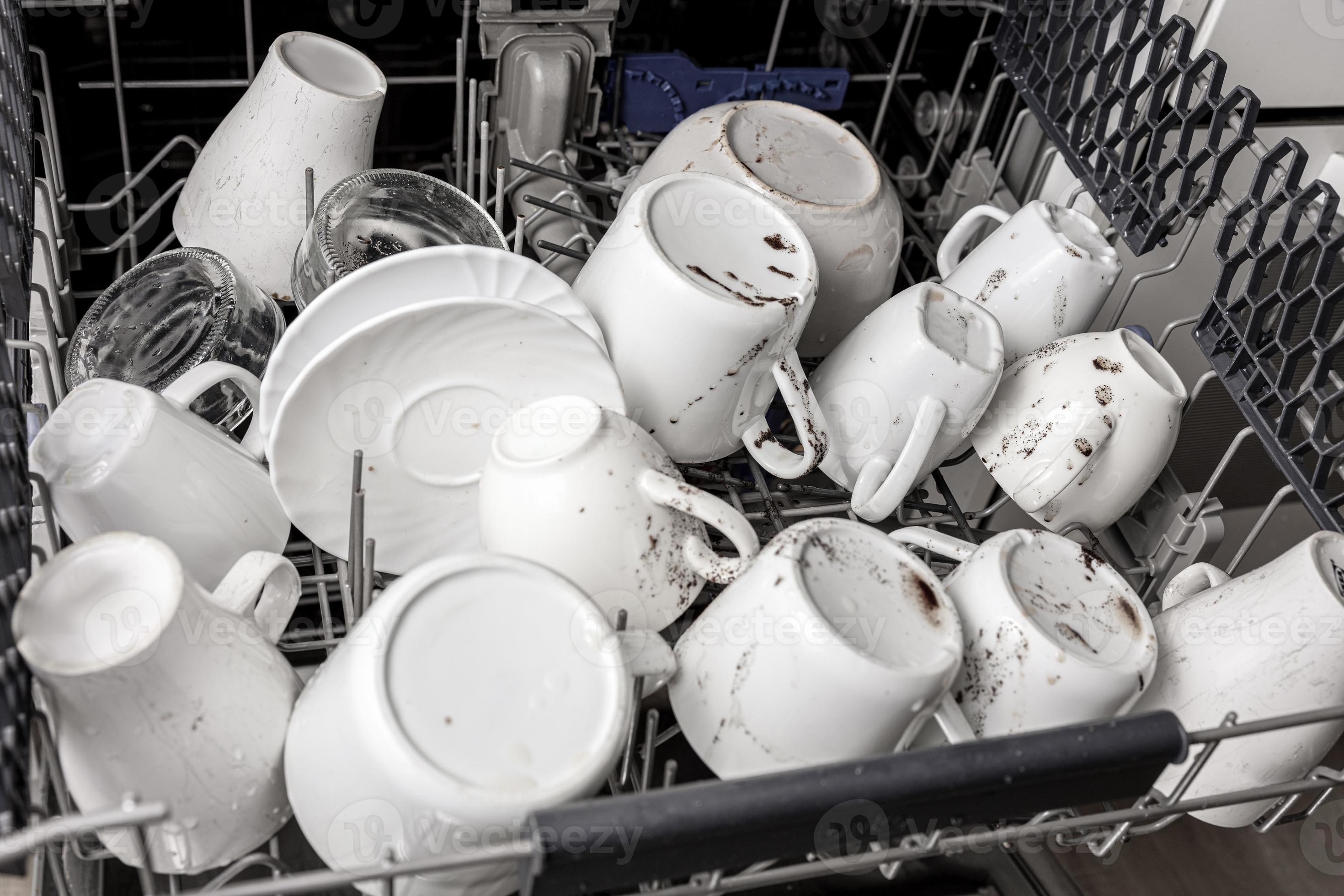 Unwashed, dirty dishes in dishwasher. Mess in the kitchen. Dirty kitchenware, plates and mugs