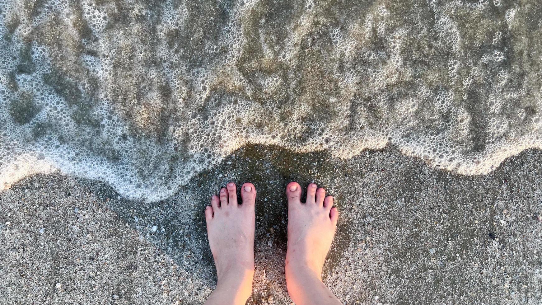 Foot on the beach with sea wave photo