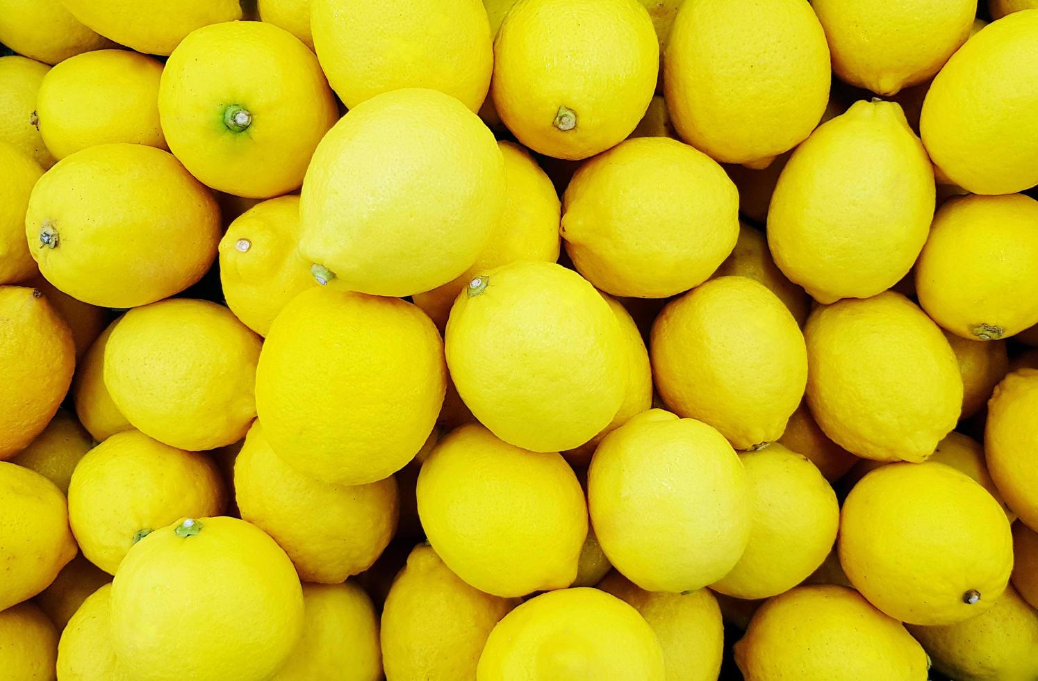 Many fresh lemon in plastic box at supermarket. Freshness vegetable or fruit at market. Pattern Group of colorful object for background. photo