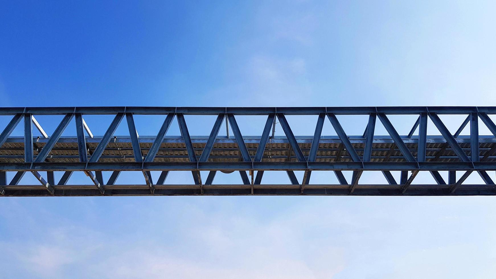 Bottom view of stainless steel electrical or communication cable tray with clear blue sky background with copy space. Iron bridge cross to air or heaven and industrial and installed system concept. photo