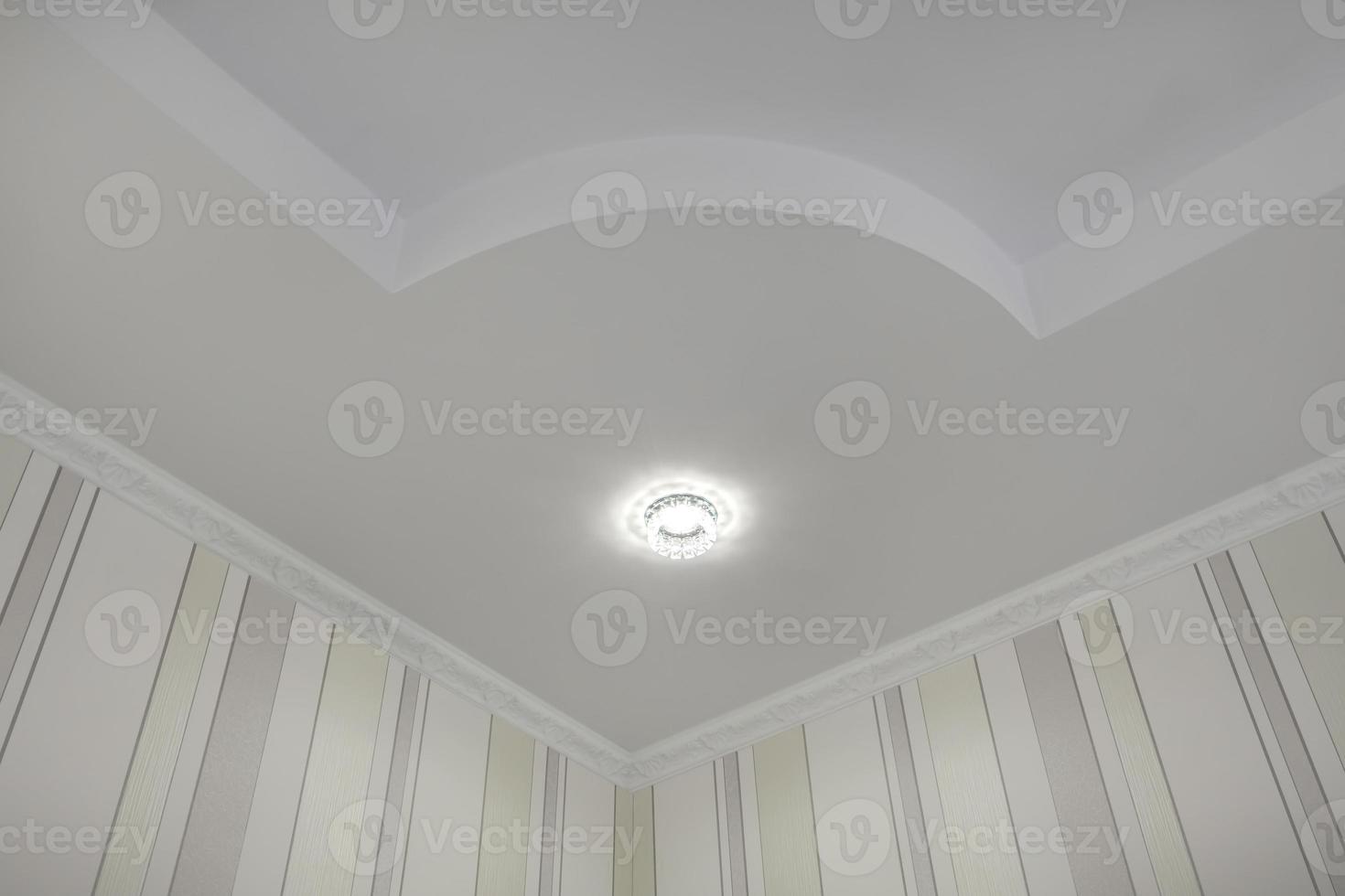 suspended ceiling with halogen spots lamps and drywall construction  with intricate crown molding in empty room in apartment or house. Stretch ceiling white and complex shape. photo