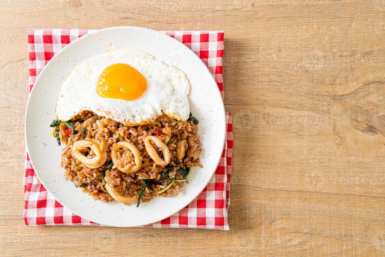 arroz frito con calamares y huevo frito cubierto de albahaca al estilo tailandés foto