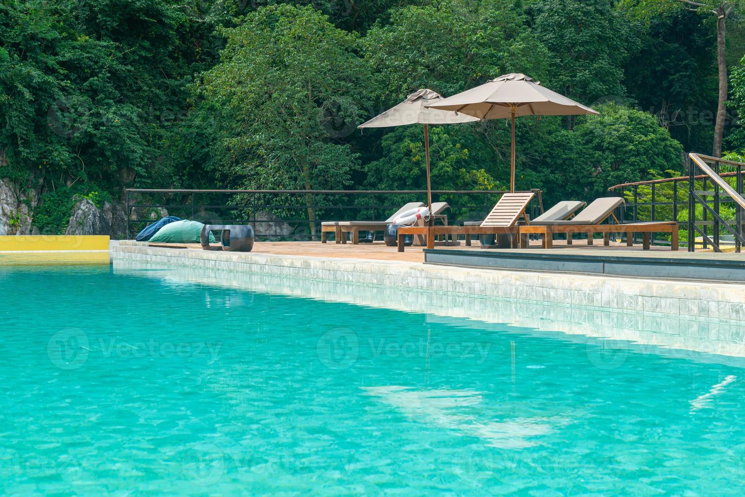 bed pool with umbrella around swimming pool photo