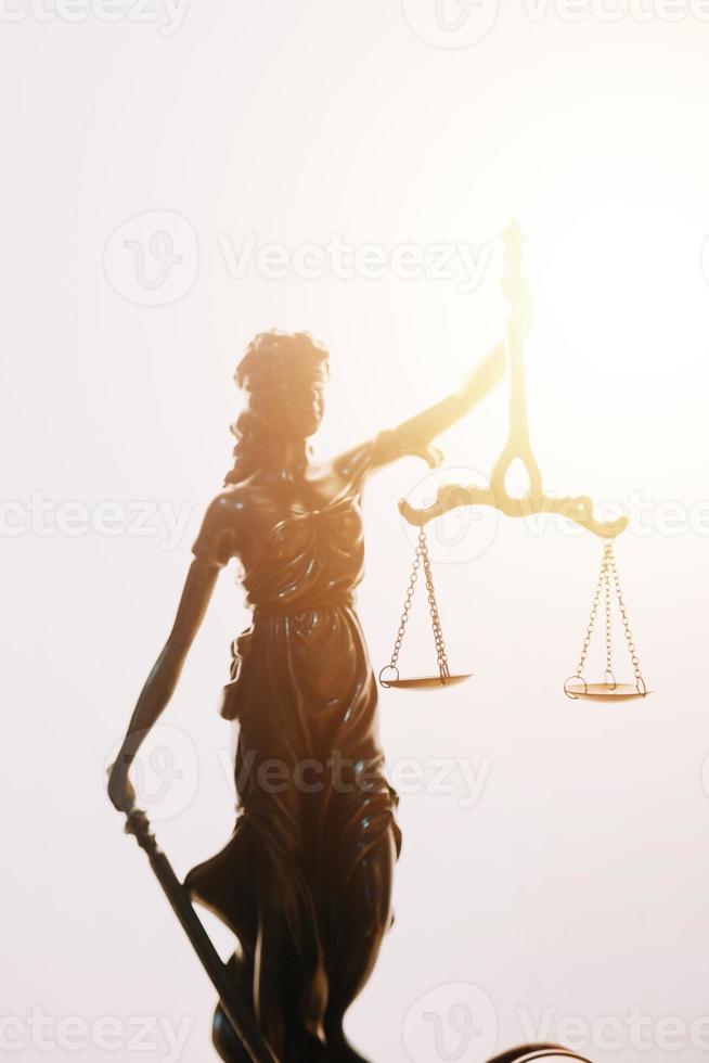 Justice and law concept.Male judge in a courtroom with the gavel, working with, computer and docking keyboard, eyeglasses, on table in morning light photo