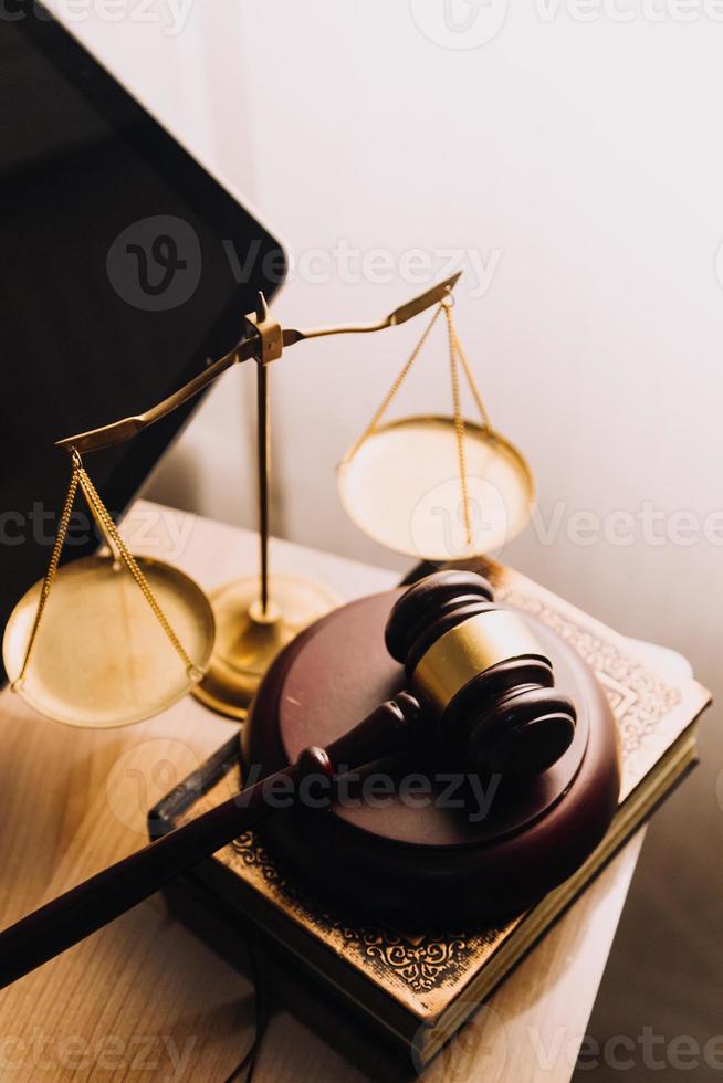 concepto de justicia y derecho. juez masculino en una sala de audiencias con el mazo, trabajando con computadora y teclado de acoplamiento, anteojos, en la mesa a la luz de la mañana foto