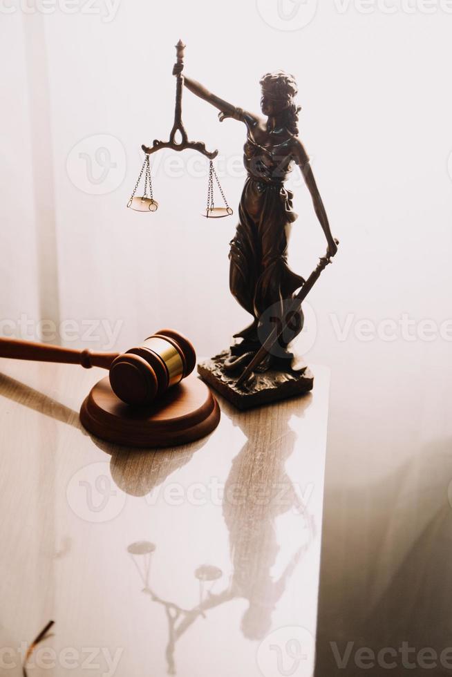 Justice and law concept.Male judge in a courtroom with the gavel, working with, computer and docking keyboard, eyeglasses, on table in morning light photo