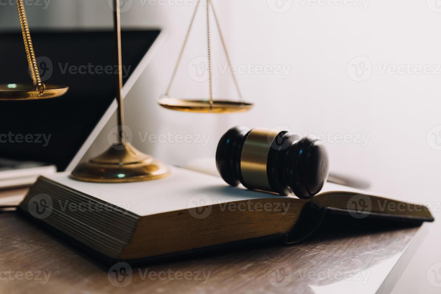 concepto de justicia y derecho. juez masculino en una sala de audiencias con el mazo, trabajando con computadora y teclado de acoplamiento, anteojos, en la mesa a la luz de la mañana foto