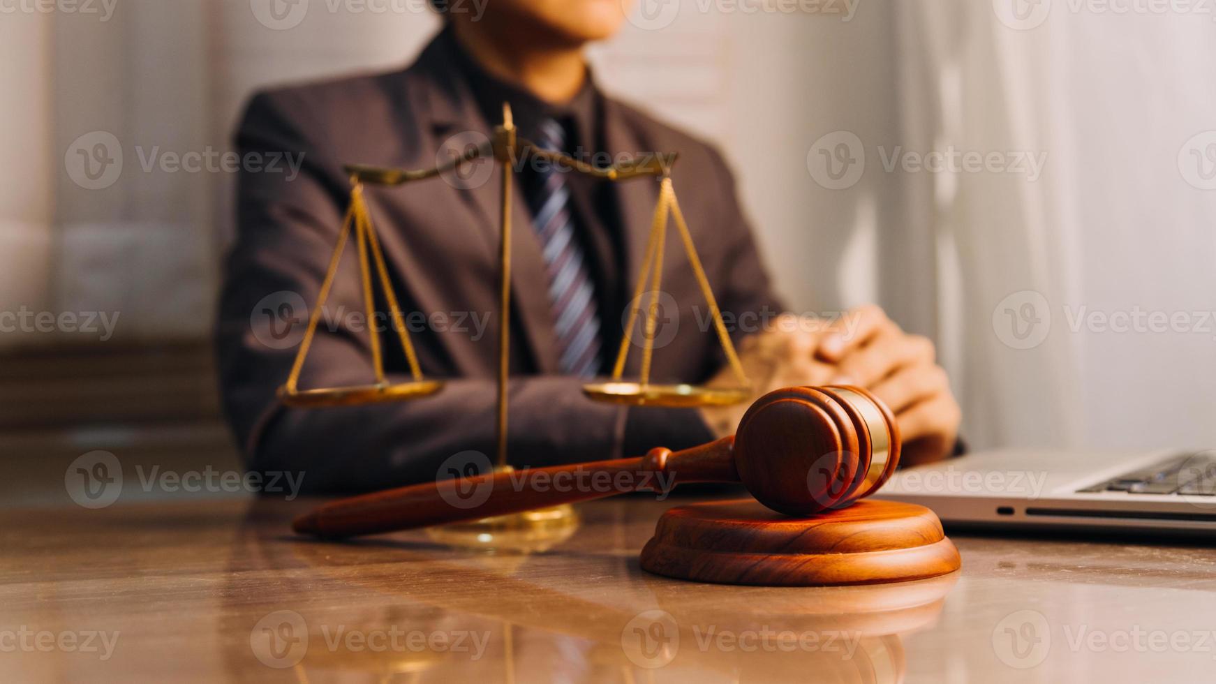 Justice and law concept.Male judge in a courtroom with the gavel, working with, computer and docking keyboard, eyeglasses, on table in morning light photo