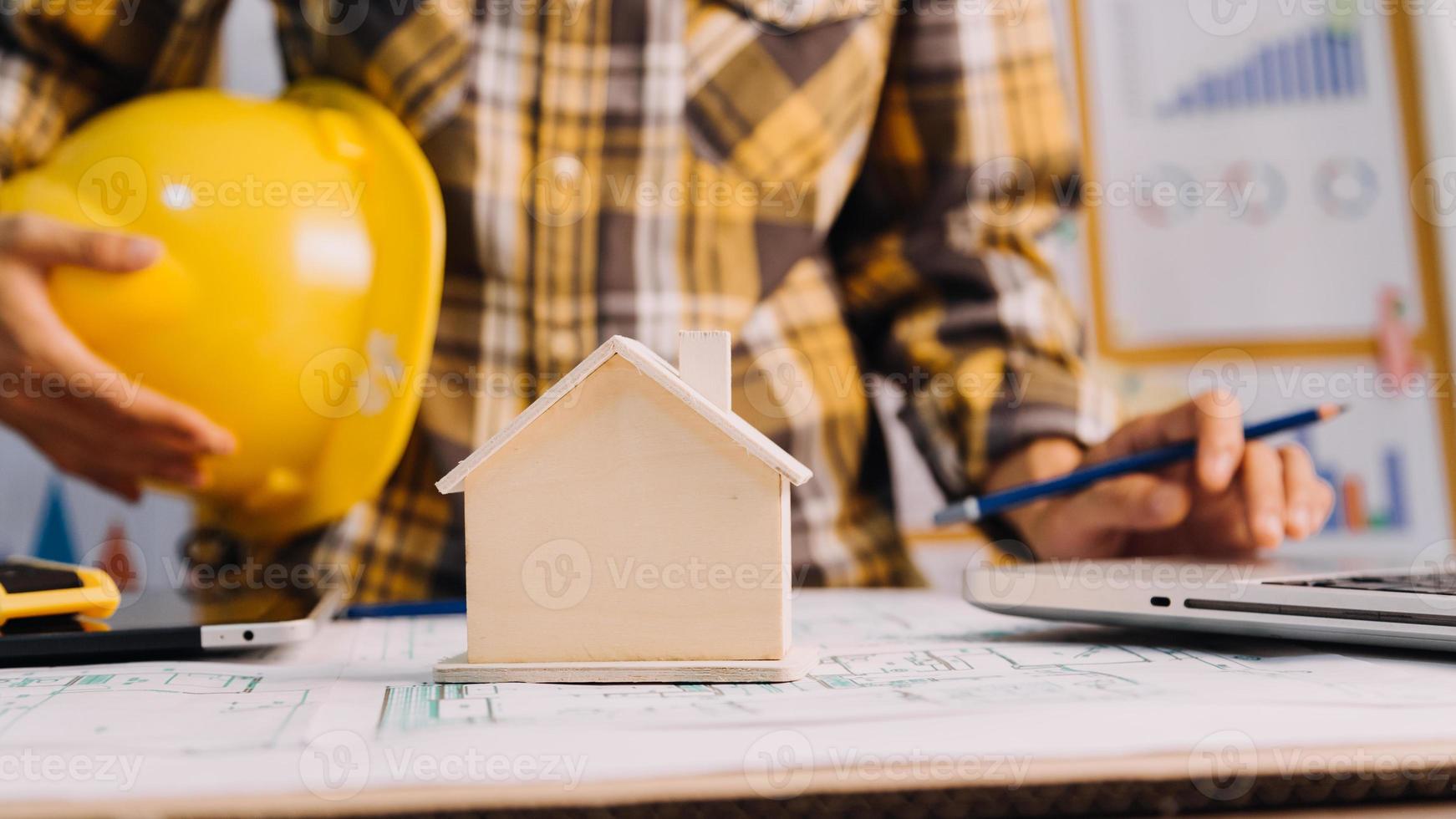 Dos colegas discutiendo el trabajo de datos y una tableta, un portátil con un proyecto arquitectónico en el sitio de construcción en un escritorio en la oficina foto