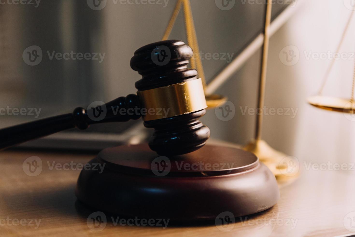 concepto de justicia y derecho. juez masculino en una sala de audiencias con el mazo, trabajando con computadora y teclado de acoplamiento, anteojos, en la mesa a la luz de la mañana foto