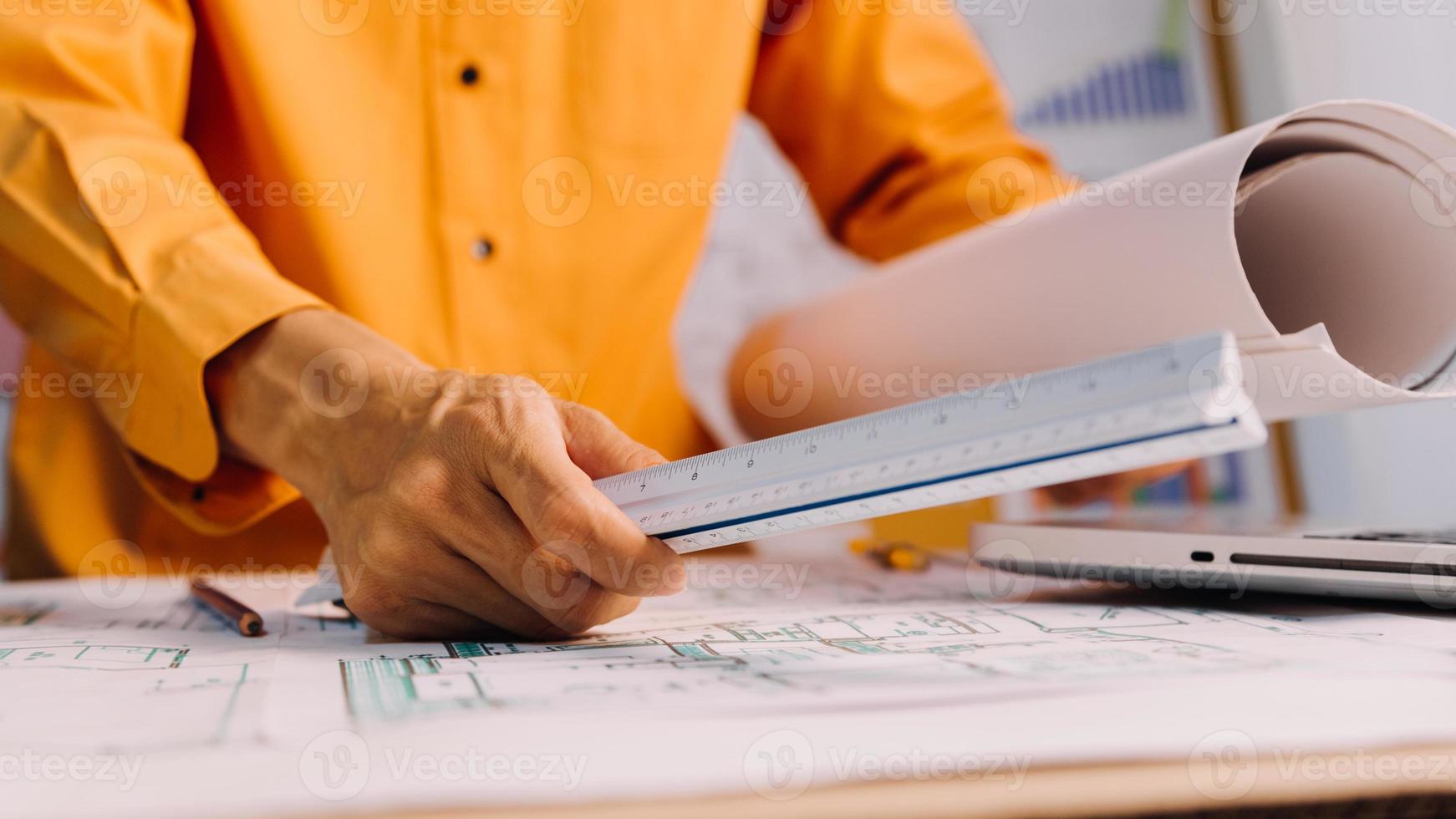 Two colleagues discussing data working and tablet, laptop with on on architectural project at construction site at desk in office photo