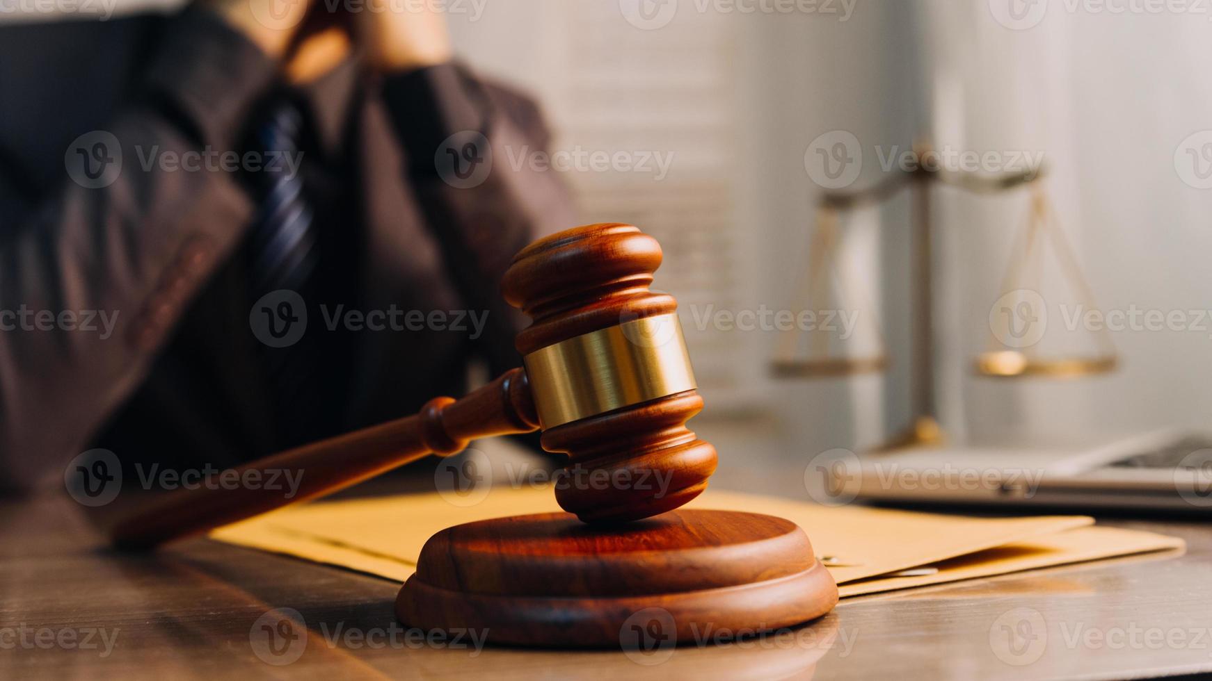 Justice and law concept.Male judge in a courtroom with the gavel, working with, computer and docking keyboard, eyeglasses, on table in morning light photo