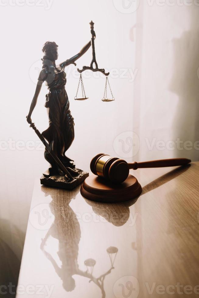 Justice and law concept.Male judge in a courtroom with the gavel, working with, computer and docking keyboard, eyeglasses, on table in morning light photo