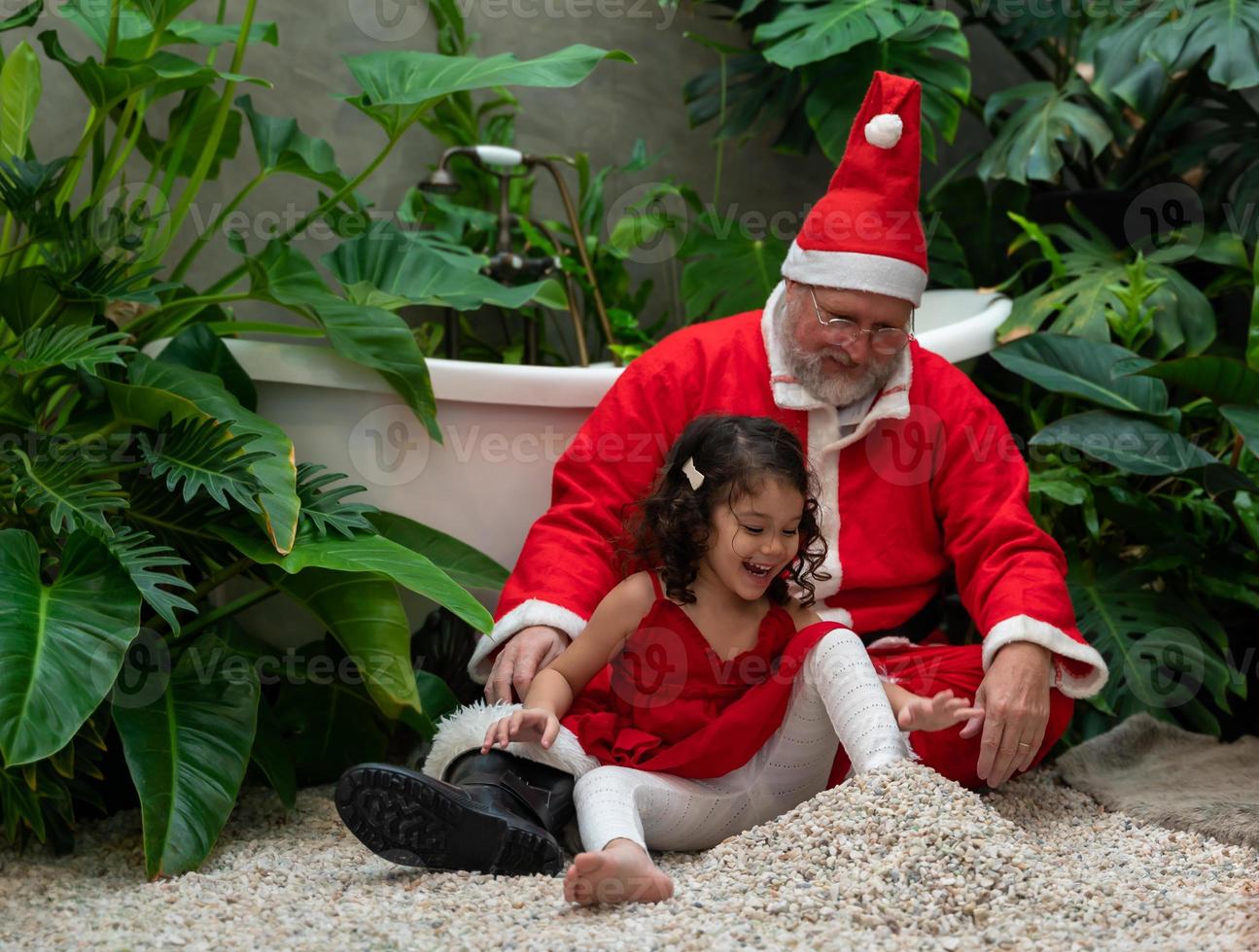 Santa Claus and cute little girl playing together at home photo