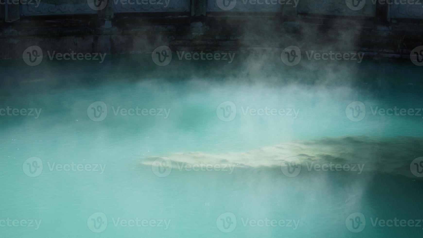 The hot spring view with the steam rising up from the hot water surface photo