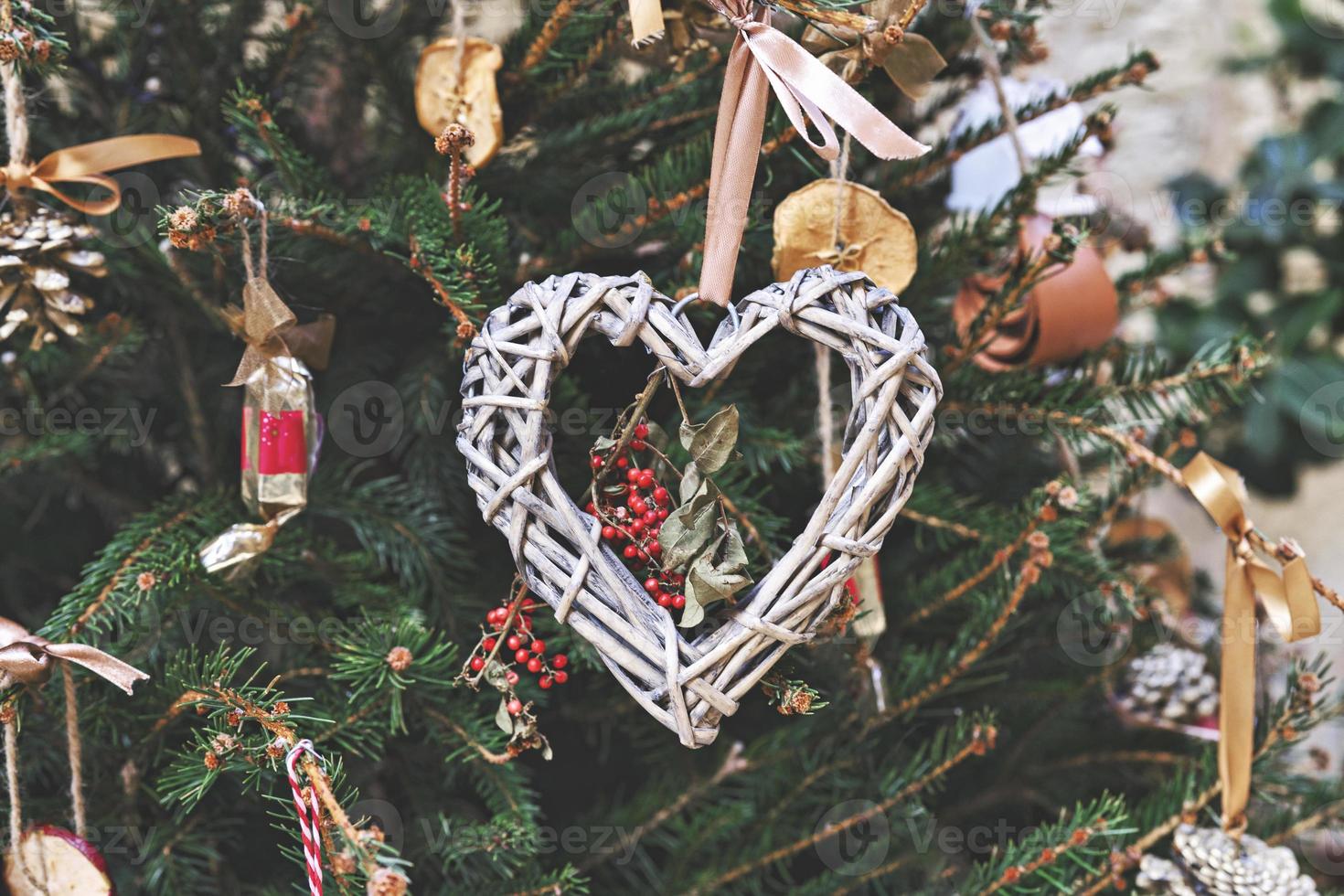 árbol de navidad decorado con una corona tejida en forma de corazón y otros adornos navideños hechos a mano sin desperdicio foto