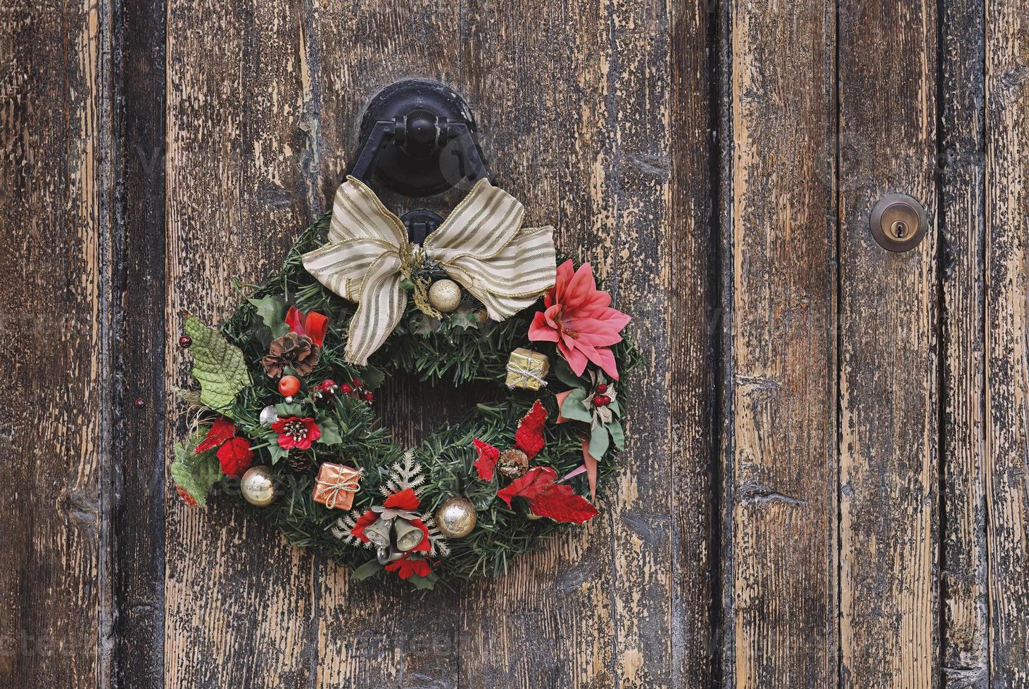 corona de Navidad sobre una antigua puerta de madera. decoración tradicional del hogar durante la navidad foto